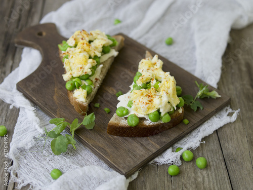 Bruschetta with green peas, cheese and egg on a wooden board. Close up, copy space