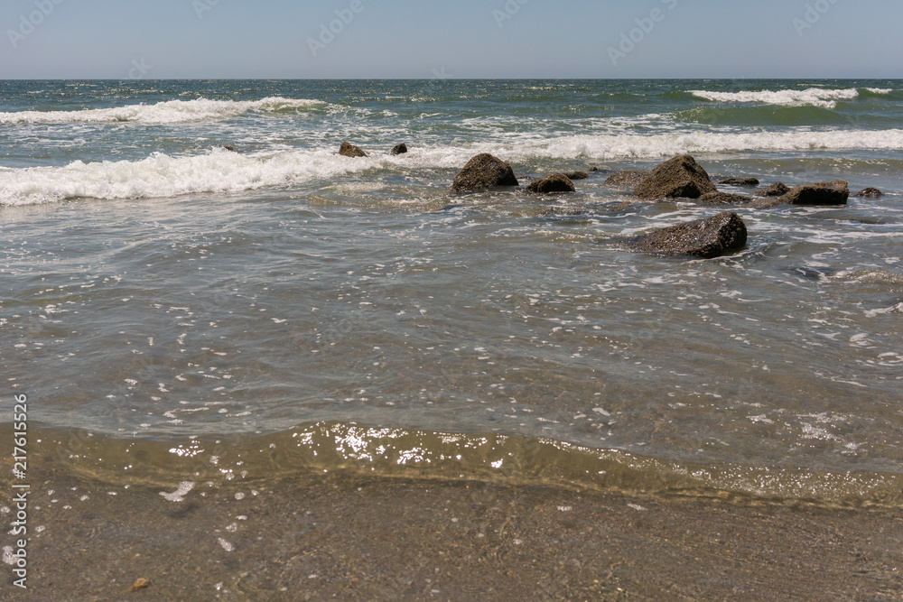 Rocks in focus with waves blurred in background at ocean Rocks in focus with waves blurred in background at ocean