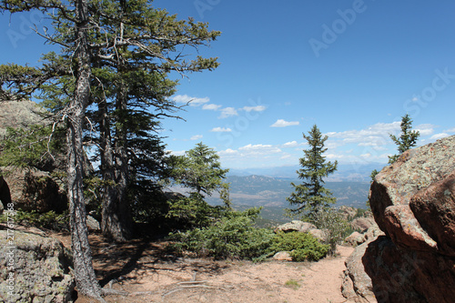 View of mountains in distance on a hike through trees and rock in Colorado © Jordan Loscher