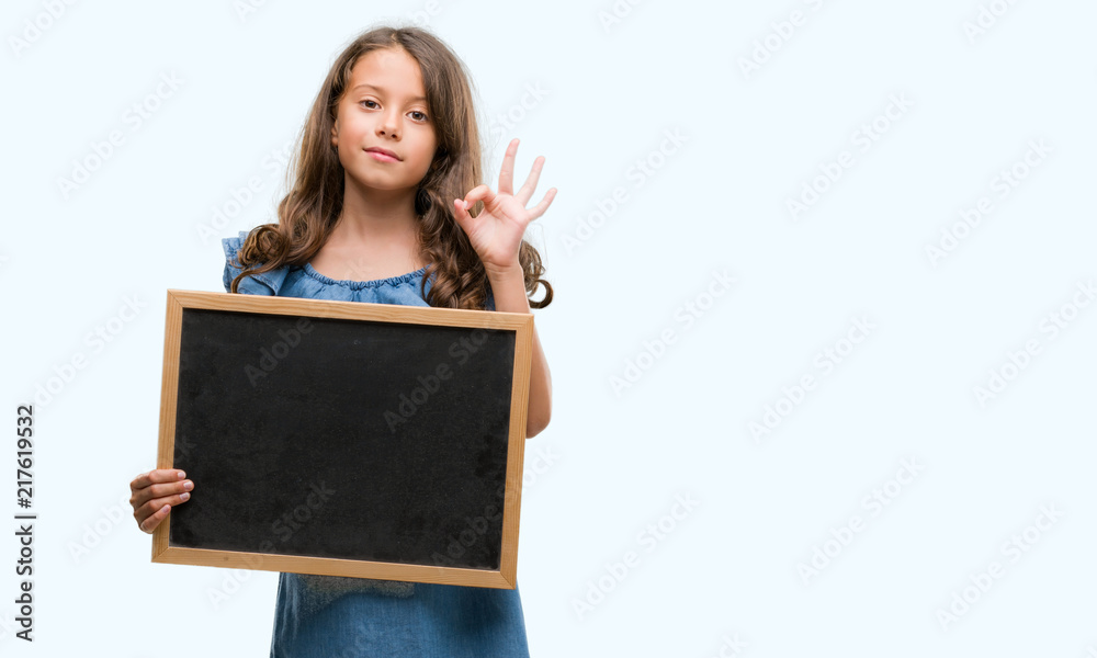 Brunette hispanic girl holding blackboard doing ok sign with fingers, excellent symbol Brunette hispanic girl holding blackboard doing ok sign with fingers, excellent symbol