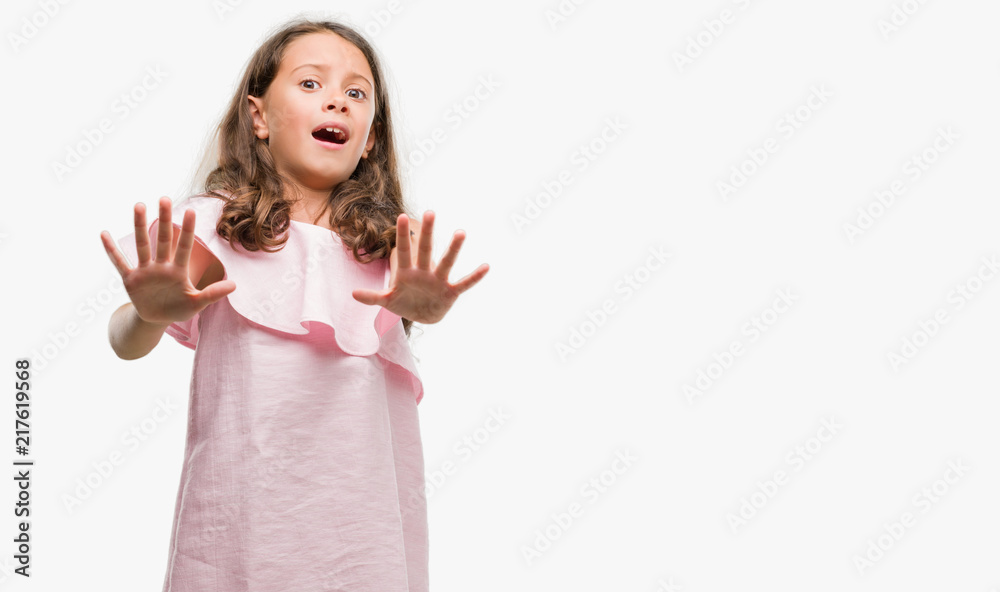 Brunette hispanic girl wearing pink dress afraid and terrified with fear expression stop gesture with hands, shouting in shock. Panic concept. Brunette hispanic girl wearing pink dress afraid and terrified with fear expression stop gesture with hands, shouting in shock. Panic concept.