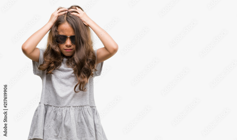 Brunette hispanic girl wearing sunglasses suffering from headache desperate and stressed because pain and migraine. Hands on head. Brunette hispanic girl wearing sunglasses suffering from headache desperate and stressed because pain and migraine. Hands on head.