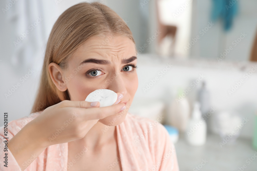Young woman holding cotton pad with fallen eyelashes indoors Young woman holding cotton pad with fallen eyelashes indoors