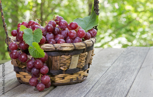 Basket of Fresh Red Grapes on a Wooden Table
