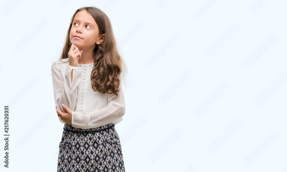 Brunette hispanic girl with hand on chin thinking about question, pensive expression. Smiling with thoughtful face. Doubt concept. Brunette hispanic girl with hand on chin thinking about question, pensive expression. Smiling with thoughtful face. Doubt concept.