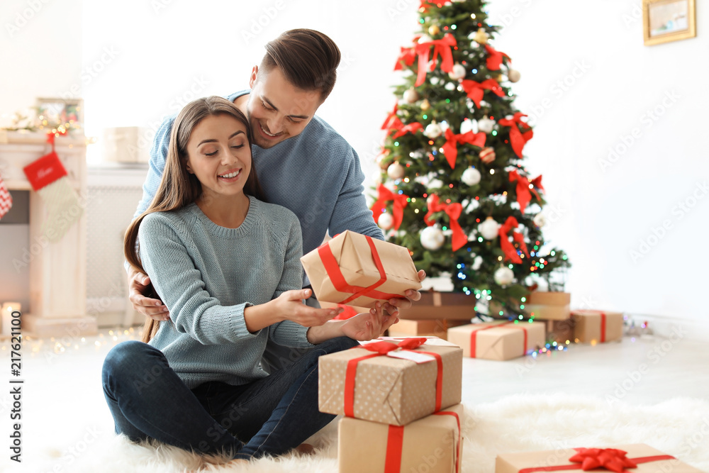 Young man giving Christmas gift to his girlfriend at home Young man giving Christmas gift to his girlfriend at home