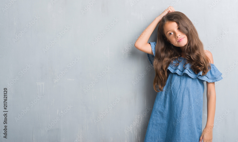 Young hispanic kid over grunge grey wall confuse and wonder about question. Uncertain with doubt, thinking with hand on head. Pensive concept. Young hispanic kid over grunge grey wall confuse and wonder about question. Uncertain with doubt, thinking with hand on head. Pensive concept.