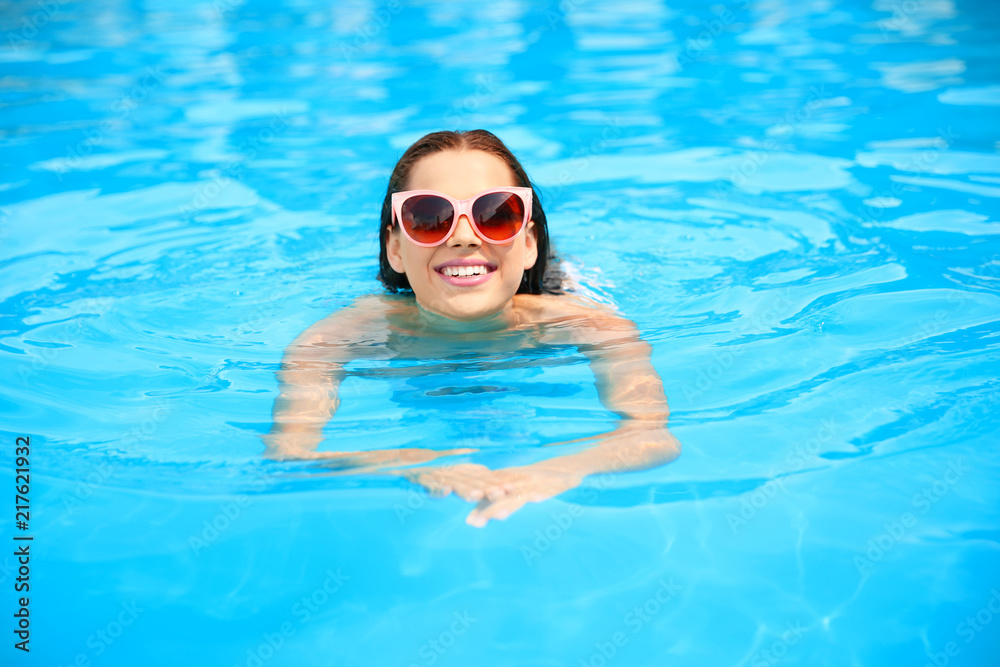Beautiful young woman swimming in blue pool