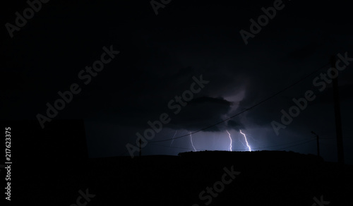 Single lightning strike in nature in a field with colours of white and blue electricity and no buildings in the landscape image