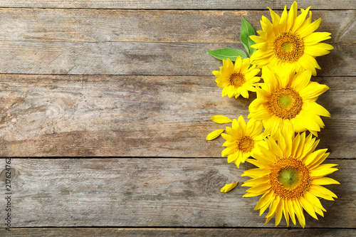 Fototapeta Naklejka Na Ścianę i Meble -  Yellow sunflowers on wooden background, top view
