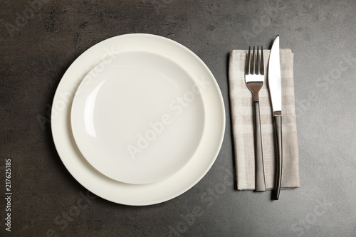 Empty dishware and cutlery on gray background, top view. Table setting