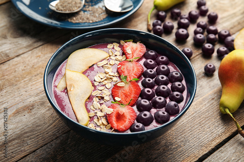Bowl with tasty acai smoothie on wooden table