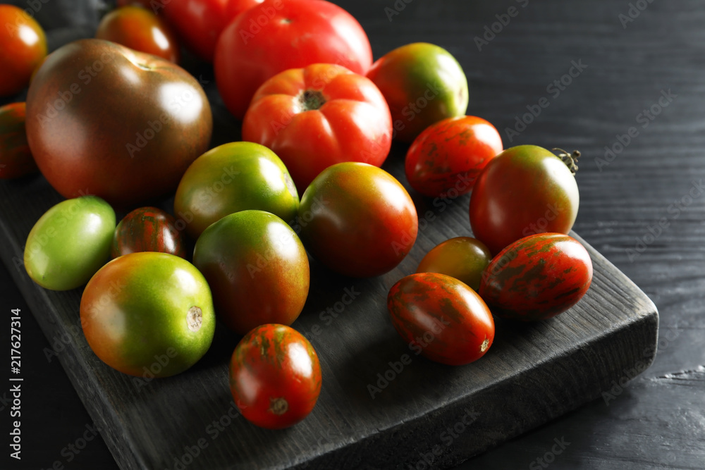 Wooden board with tasty tomatoes on table Wooden board with tasty tomatoes on table