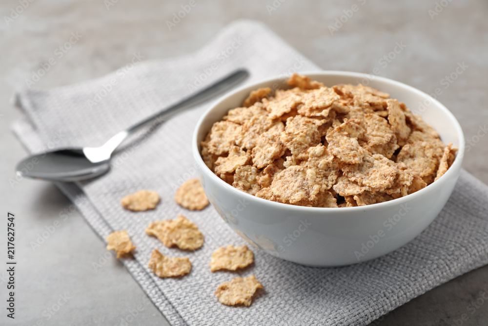 Bowl with cornflakes on gray table. Whole grain cereal for breakfast Bowl with cornflakes on gray table. Whole grain cereal for breakfast