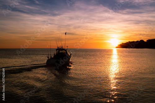 Boat leaving port to head out fishing, fishing boat during sunrise. 