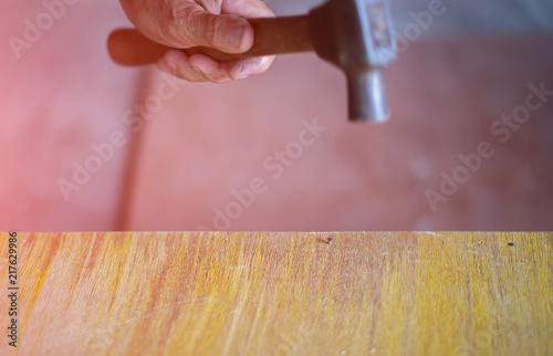 The hand of a carpenter holding a hammer is nailed to a wooden p