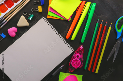 School and office stationery on a background of a dark wooden board.