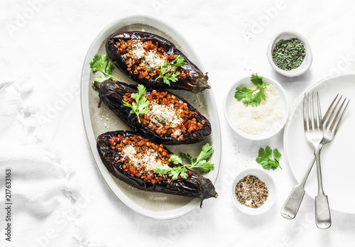 Stuffed lentils roasted eggplant - delicious healthy vegetarian served lunch  table. On a light background, top view