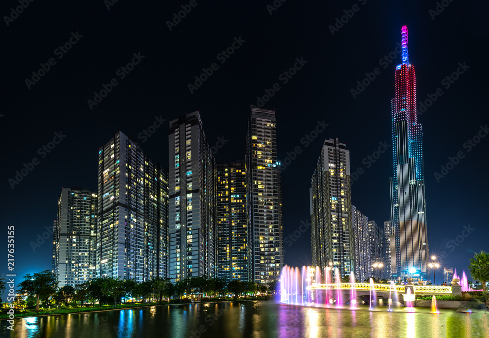 Ho Chi Minh City, Vietnam - August 1st, 2018: A state of art fountain at night with colorful lights shimmering, behind the skyscrapers in the urban park development in Ho Chi Minh City. Minh, Vietnam