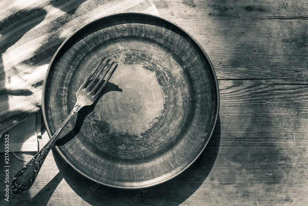 Empty clay plate with a fork on an old wooden table, top view, copy space Empty clay plate with a fork on an old wooden table, top view, copy space