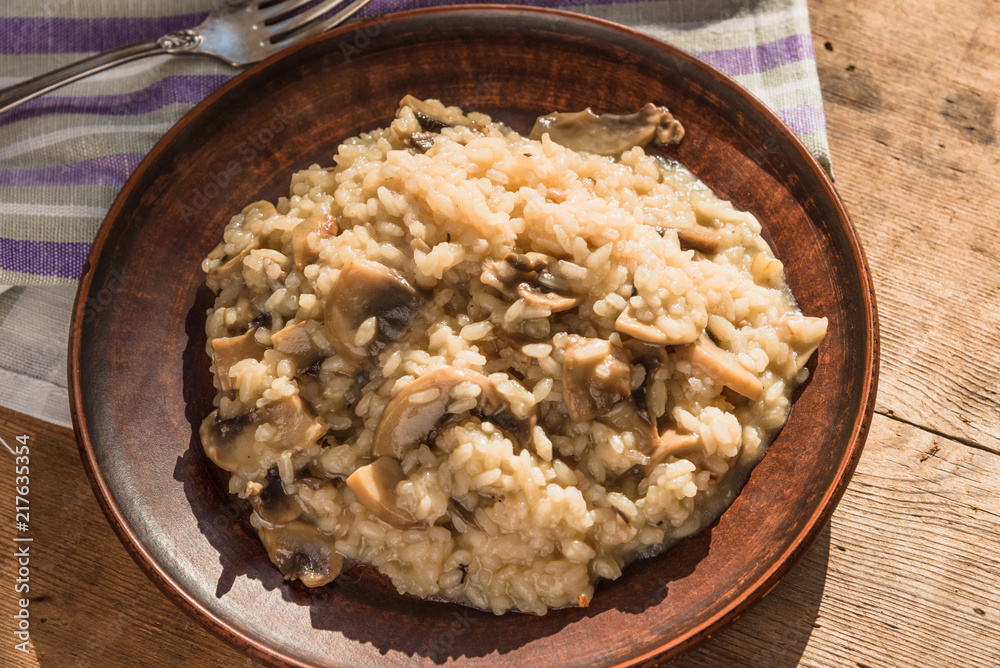 Italian traditional dish - risotto with mushrooms in a clay plate on an old wooden table, top view, copy space for a recipe Italian traditional dish - risotto with mushrooms in a clay plate on an old wooden table, top view, copy space for a recipe