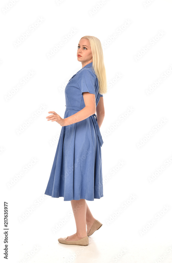 full length portrait of blonde girl wearing blue dress, standing pose. isolated on white studio background. full length portrait of blonde girl wearing blue dress, standing pose. isolated on white studio background.
