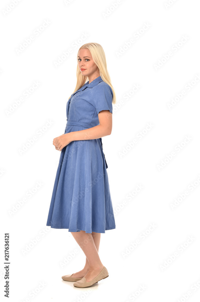 full length portrait of blonde girl wearing blue dress, standing pose. isolated on white studio background. full length portrait of blonde girl wearing blue dress, standing pose. isolated on white studio background.
