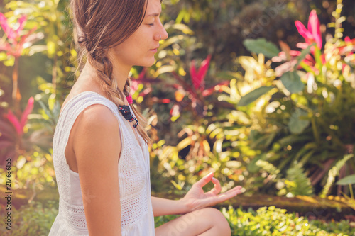 Young woman practicing yoga - meditation in the tropical garden.