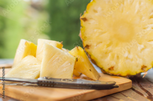 Pineapple slices kept on a chopping board with a knife and chopped sliced pineapple with copy space