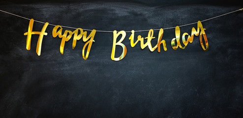 Happy birthday golden garland at a dark wall