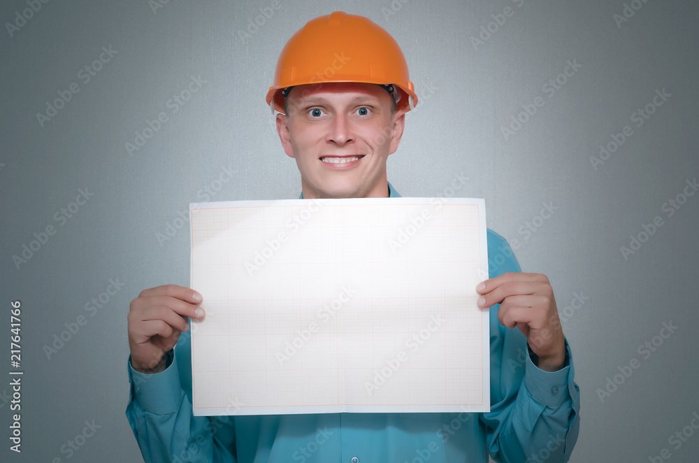 Happy builder construction worker is holding in hand a plan draft document isolated on gray background. Happy builder construction worker is holding in hand a plan draft document isolated on gray background.