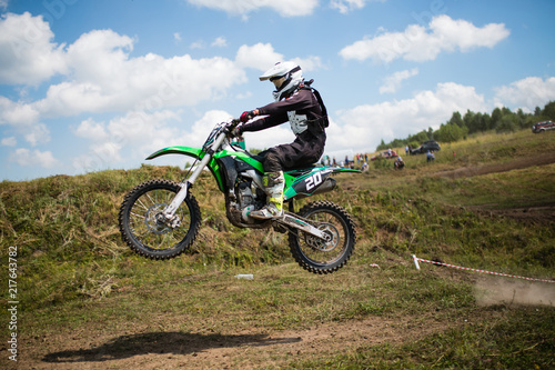 Fototapeta Naklejka Na Ścianę i Meble -  motocross. A motorcycle racer participates in motocross trains in flight, jumps and takes off on a springboard against. concept of active extreme rest. Smoke and dust are flying from under the wheels