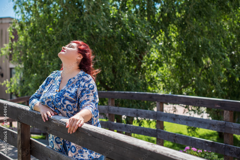 A woman of plus size, American or European appearance walks at park enjoying life. A middle age lady with excess weight, rest at city park A woman of plus size, American or European appearance walks at park enjoying life. A middle age lady with excess weight, rest at city park