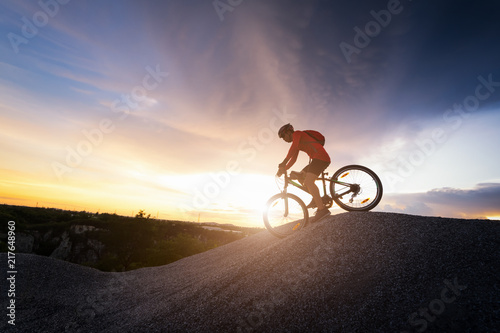 Young man riding mountain bike on the background of mountains at sunset