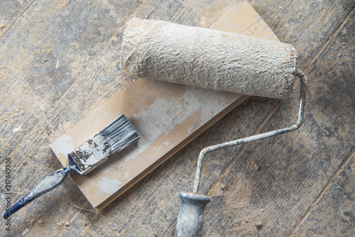 Painting roller and brush on the wooden floor white color
