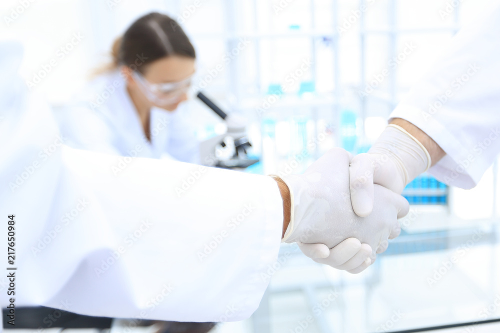 Doctors in lab coats greeting each other with handshake Doctors in lab coats greeting each other with handshake