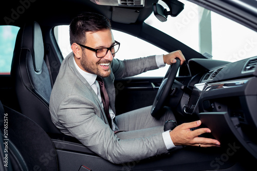 Handsome businessman is sitting in a new car in car dealership © zorandim75