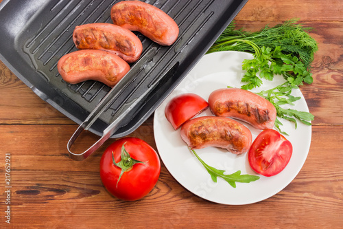 Top view of grilled sausages with greens and tomatoes