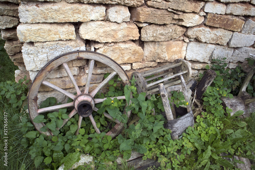Open air museum of antique peasant  things, old wheel near the brick wall