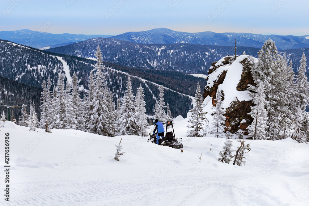 Snowmobile rides on snow-covered mountain. Winter landscape. View on top of Mountain Utuya in ski resort Sheregesh.  Russia, Altay Mountains.