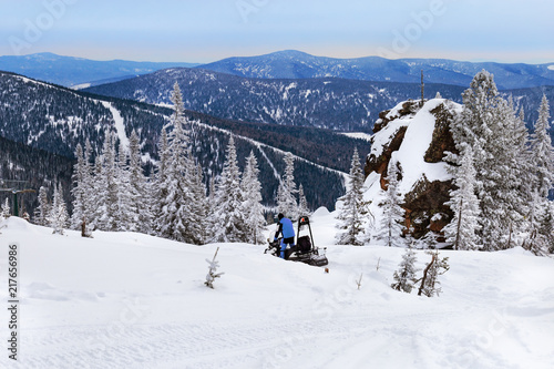 Snowmobile rides on snow-covered mountain. Winter landscape. View on top of Mountain Utuya in ski resort Sheregesh. Russia, Altay Mountains.