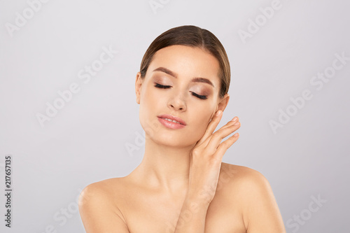 Portrait of beautiful woman with natural make up touching her face. Beauty young woman with fresh clean perfect skin. Skin care concept. Cosmetology, beauty and spa. Facial treatment. Natural skin.