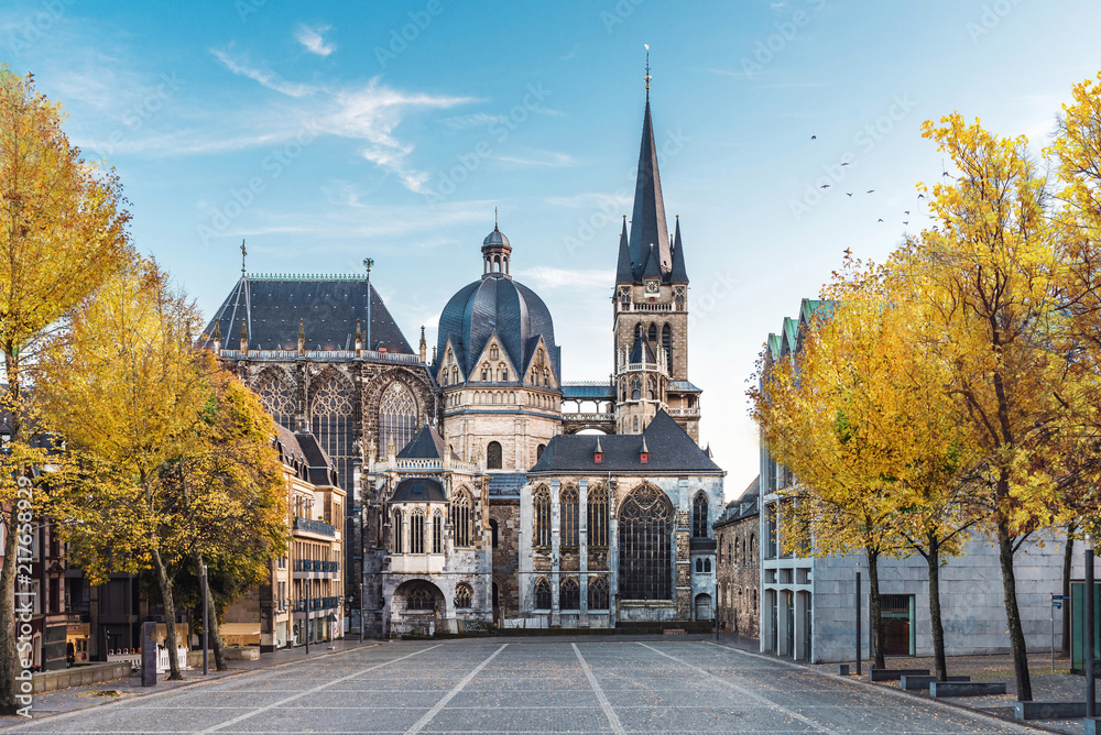 Naklejka premium Niemiecka katedra w Aachen podczas spadku z żółtymi liśćmi przy drzewami z niebieskim niebem