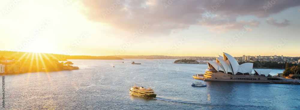 Fototapeta premium Pejzaż portu w Sysney z porannym wschodem słońca i łodzią na morzu