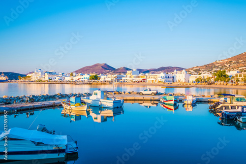 Reflection of an old fishing boat moored at small dock, Paros island, Greece. Beautiful view of fishing boats with reflection on sea surface at sunset