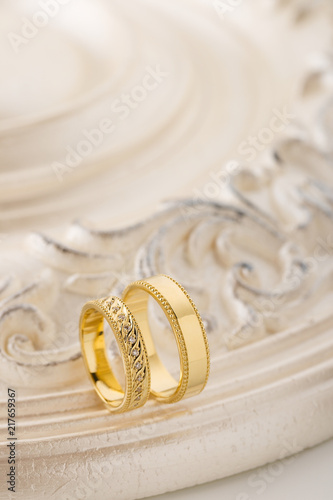 Two gold wedding rings on beige background