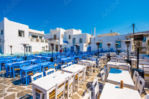 Colored tables and chairs outdoors in traditional Greek cafe. Typical Greek taverna in Naoussa port, Paros island, Greece