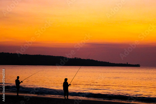 Fishermen on the beach on the island of Bali at sunset.