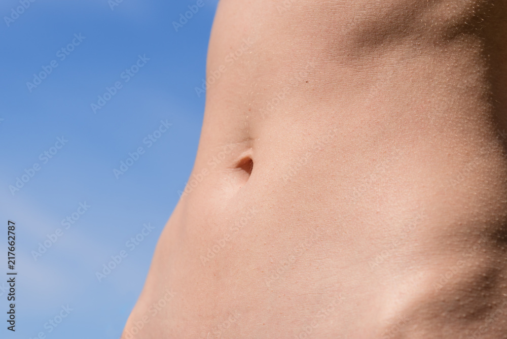Waist of a young slender girl close-up on a sky background Waist of a young slender girl close-up on a sky background