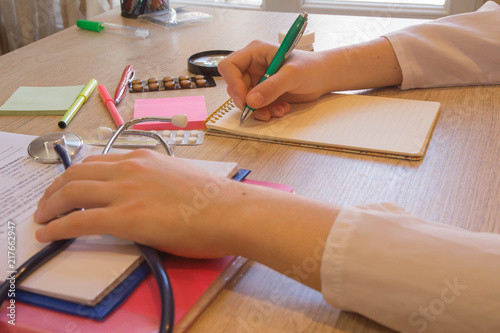 Healthcare and medical concept. Female medical doctor writing something sitting at her office